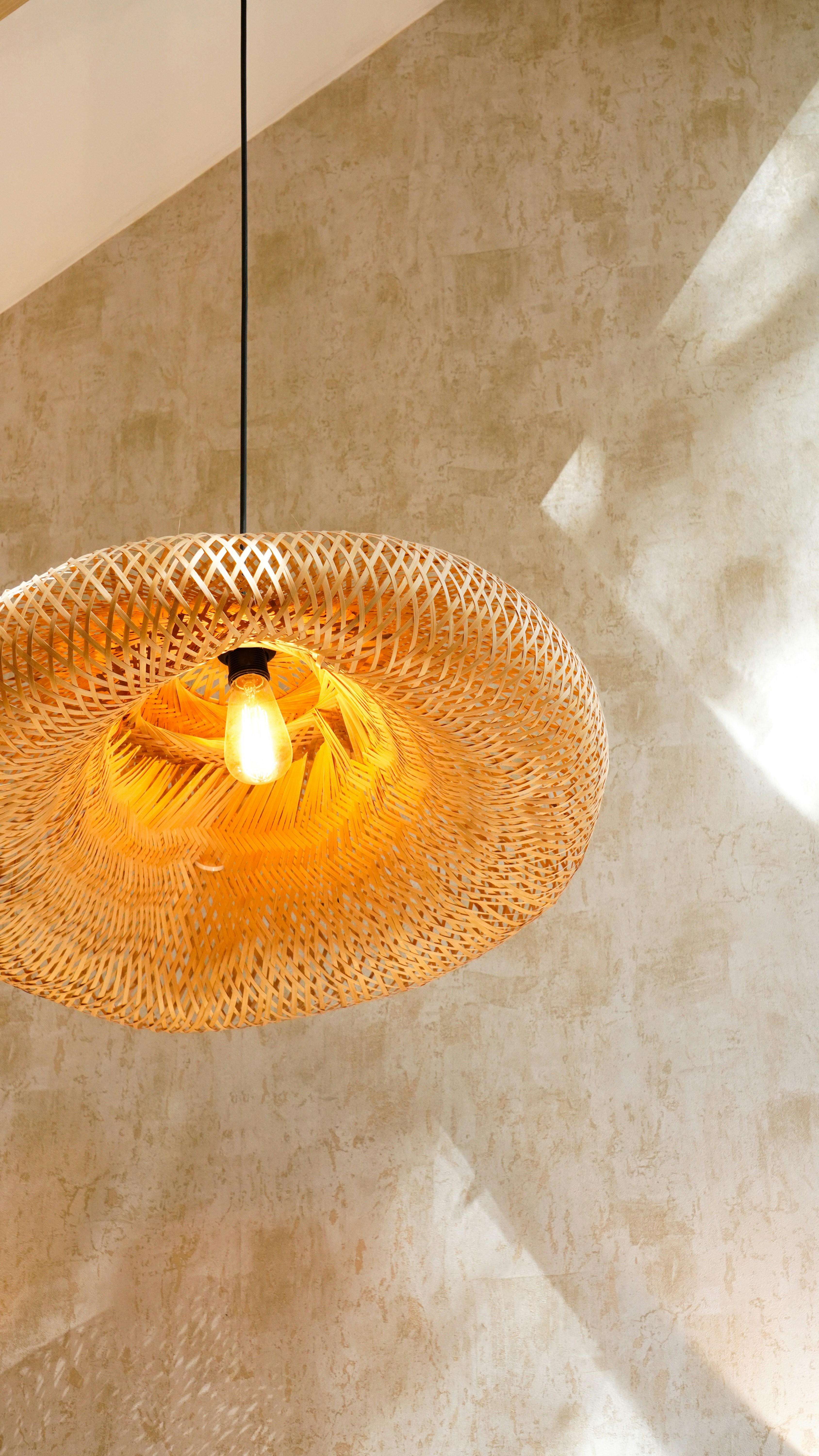 Suspension en bambou sur un mur de plâtre au soleil